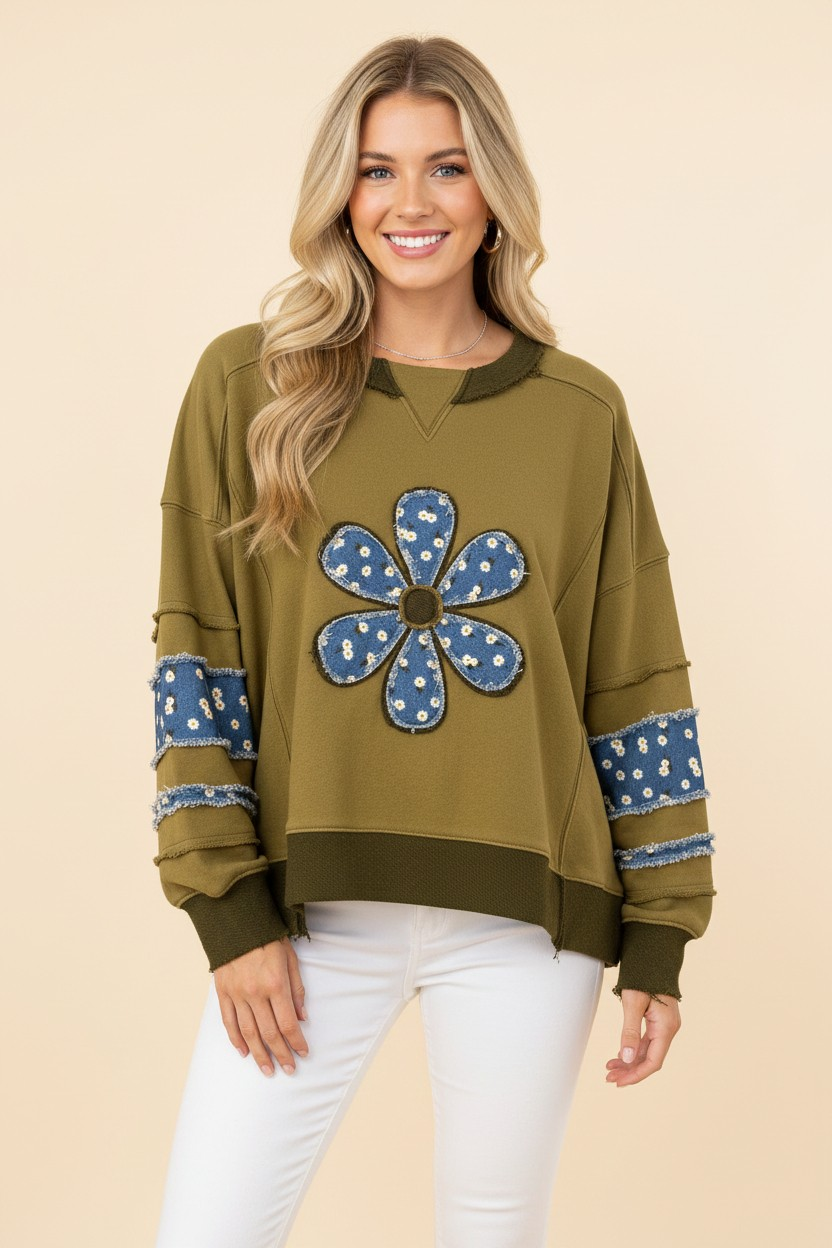 Model wearing an olive green top with a blue floral flower appliqué and matching sleeve patches.