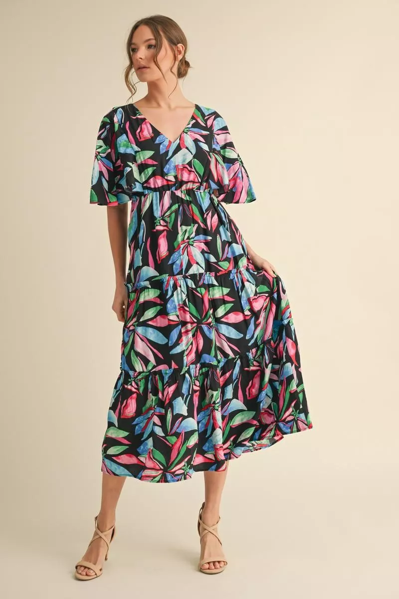 Black tiered midi dress with pink, green, and blue tropical leaf print, a V-neckline, and flutter sleeves.