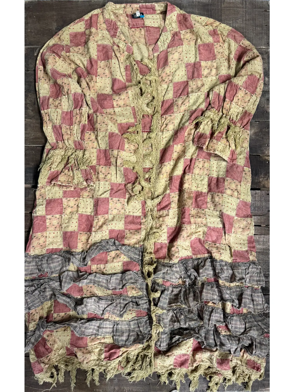 Dusty rose and cream checkerboard patchwork duster with fringed front trim, two patch pockets, and a tiered gray gingham ruffle hem with fringe.