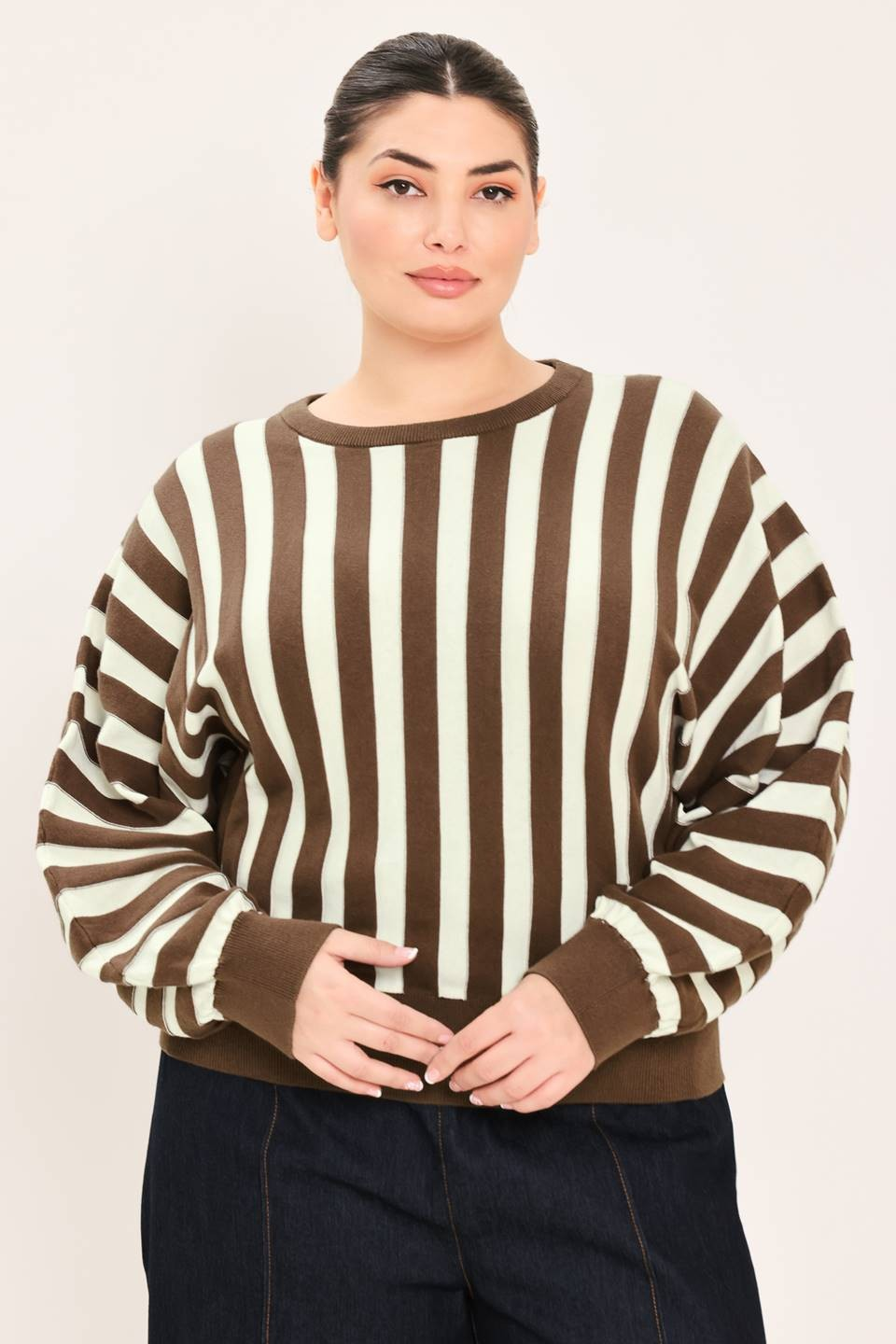 Model wearing a brown and cream vertically striped long-sleeve sweater with brown ribbed trim