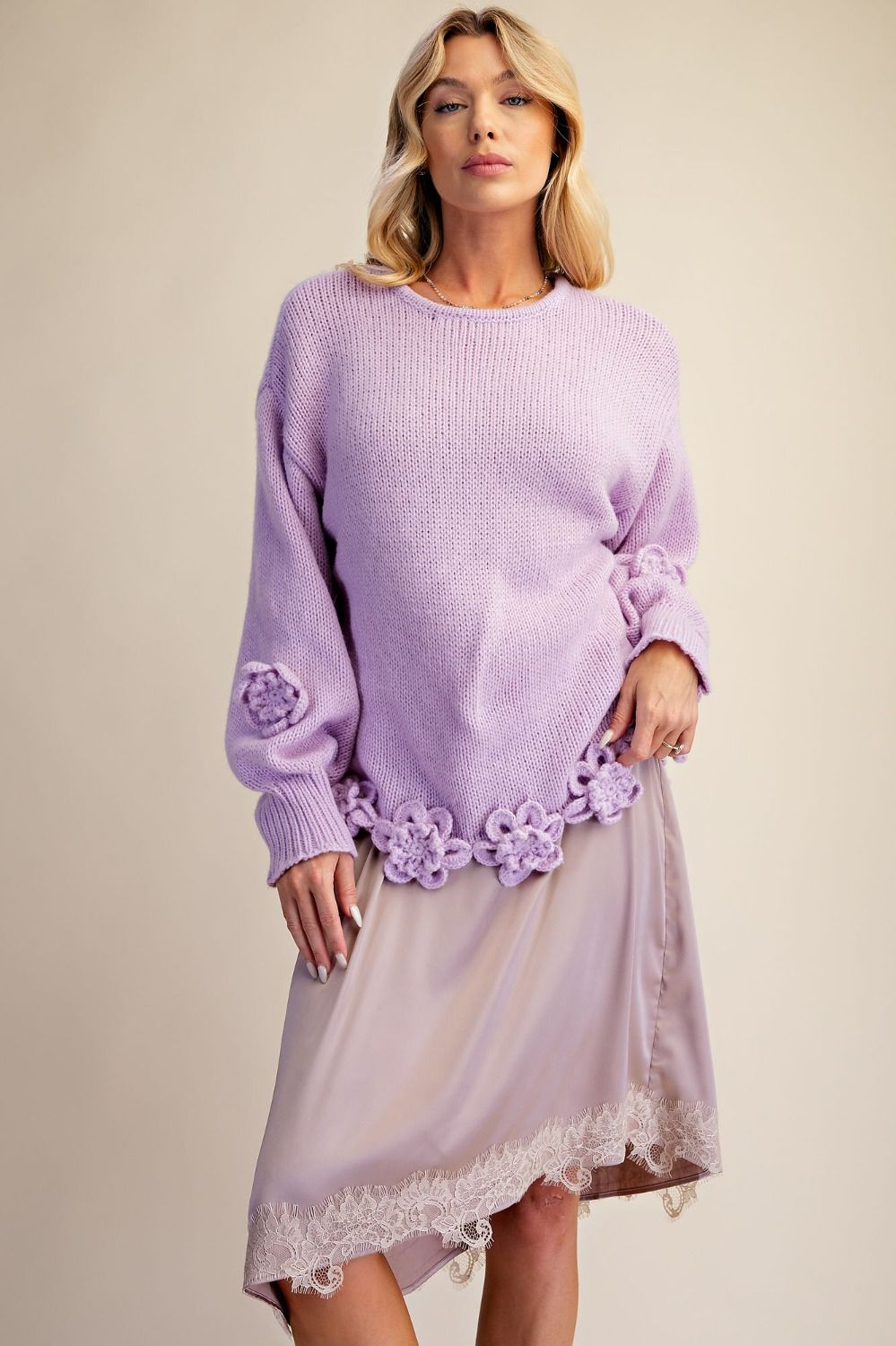 Lavender knit sweater with dimensional floral appliqués along the hem and sleeves, styled with a lace-trim skirt.