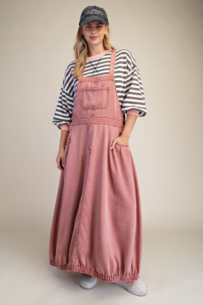 Dusty rose denim bib-overall maxi dress with bubble hem, styled with a black-and-white striped top