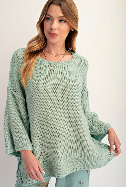 Model wearing a seafoam green open-knit sweater with wide sleeves and a longline hem.