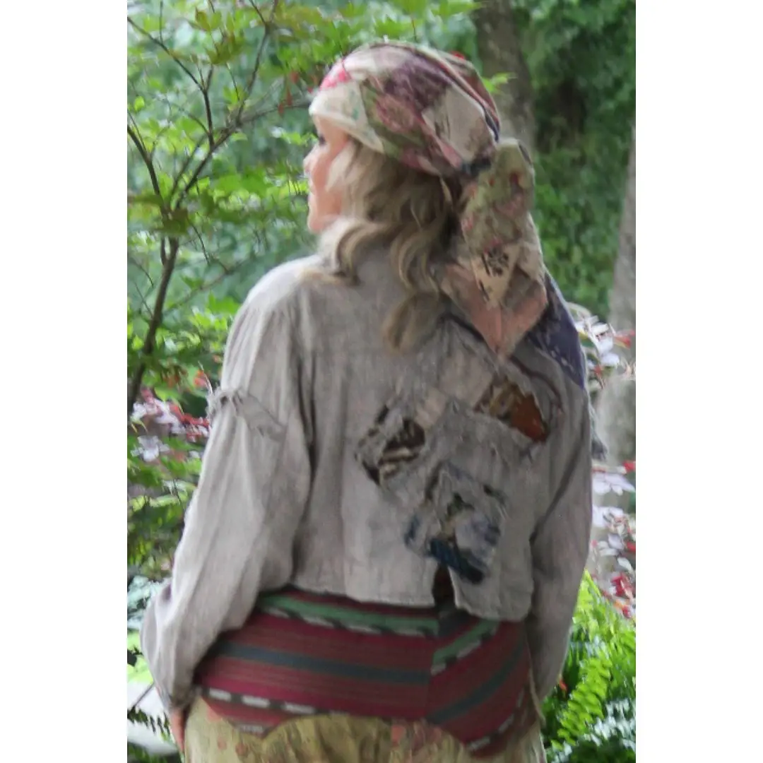 Back view of gray-taupe cropped patchwork jacket styled with a patterned skirt outdoors.