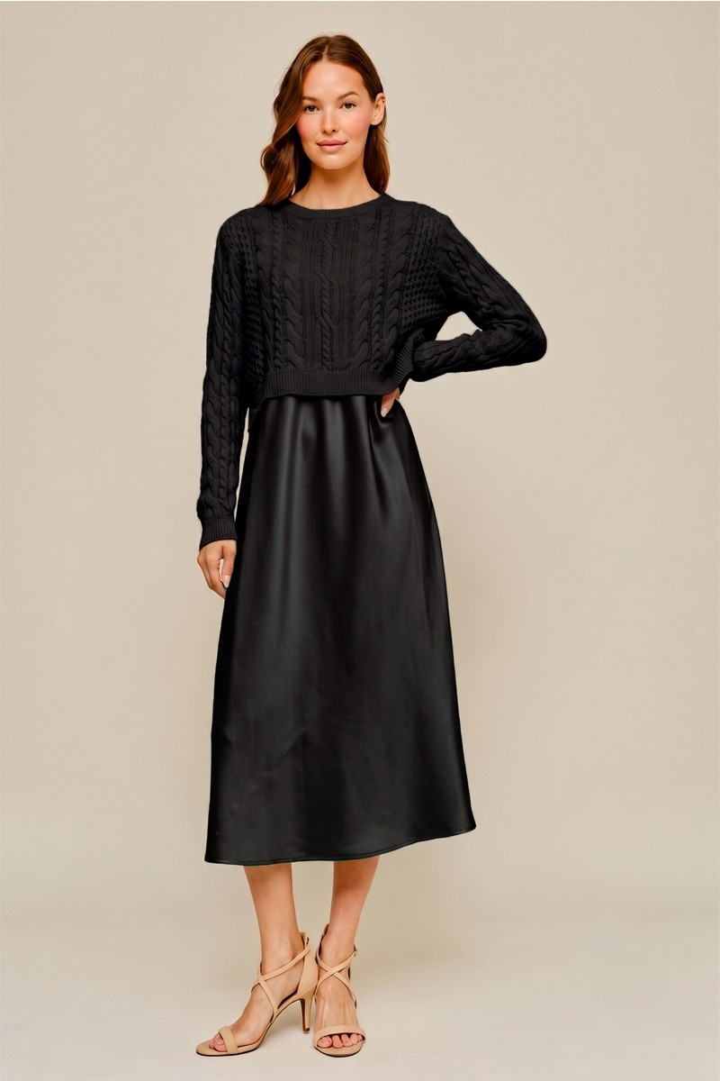 Model wearing a black cable-knit crewneck sweater with a black satin midi skirt and strappy heels
