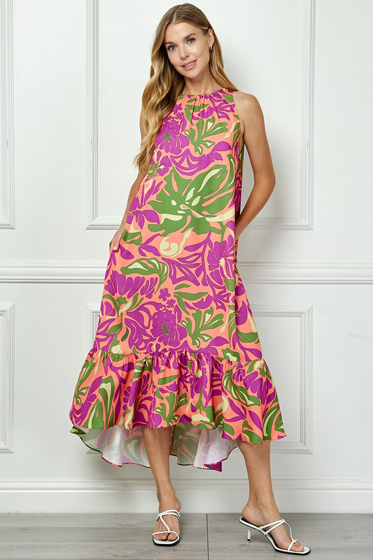 Model wearing a peach halter-style dress with purple and green botanical print and a ruffled high-low hem.