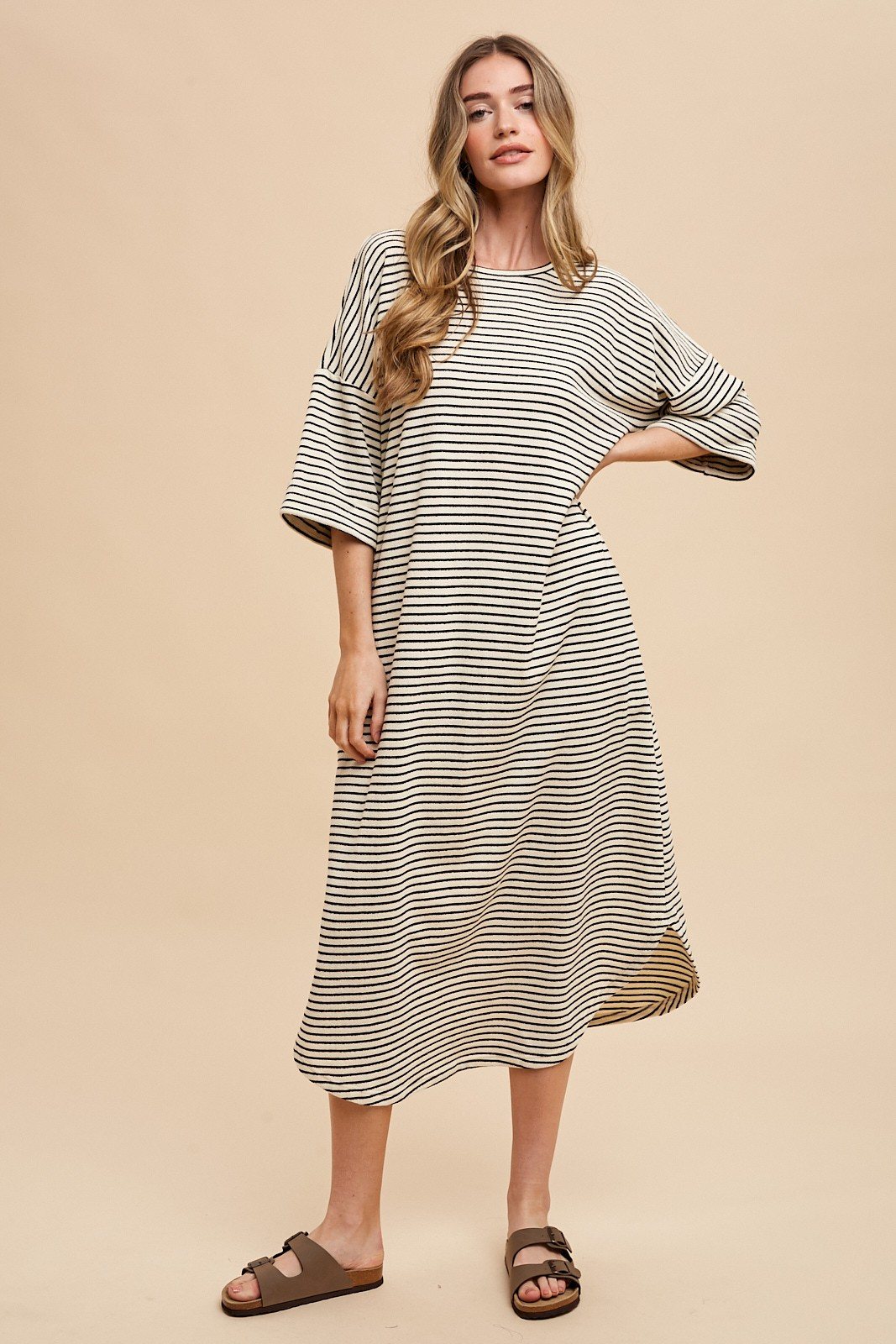 Model wearing a black and cream striped oversized midi t-shirt dress with brown slide sandals