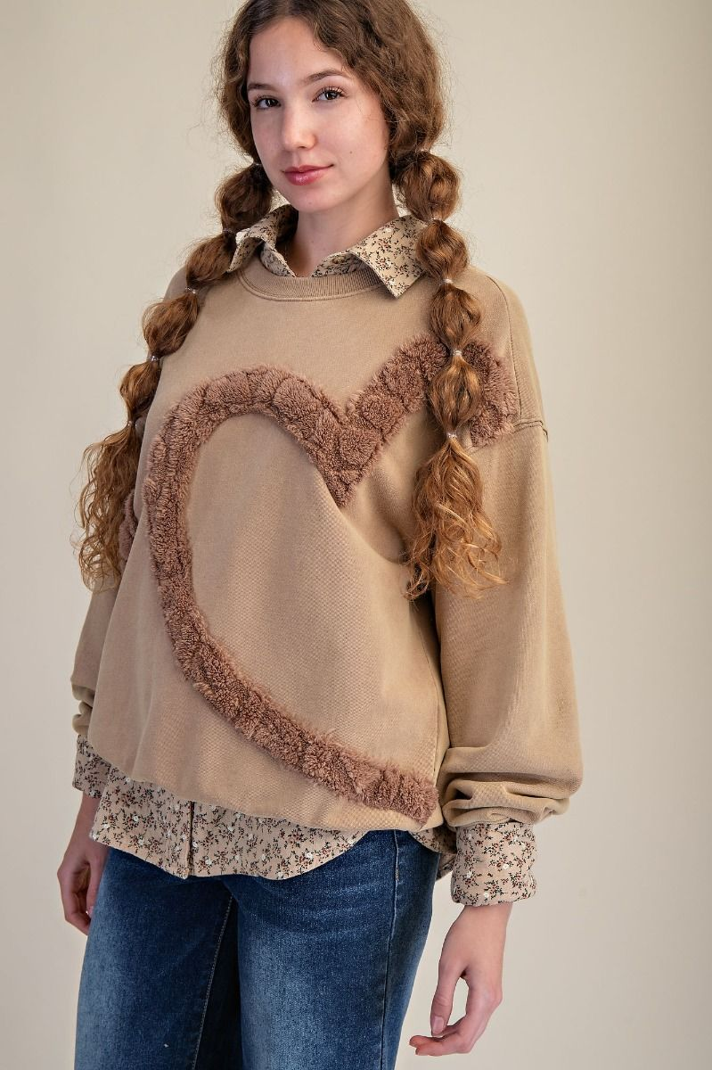 Taupe crewneck sweatshirt with a large brown textured heart outline, styled over a floral collared shirt with jeans.