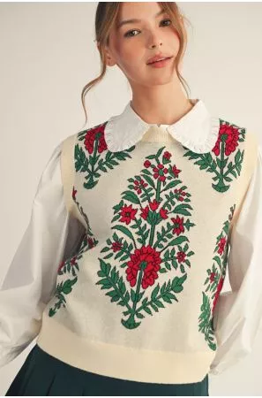 Cream sweater vest with red floral and green botanical motifs, styled over a white collared blouse.